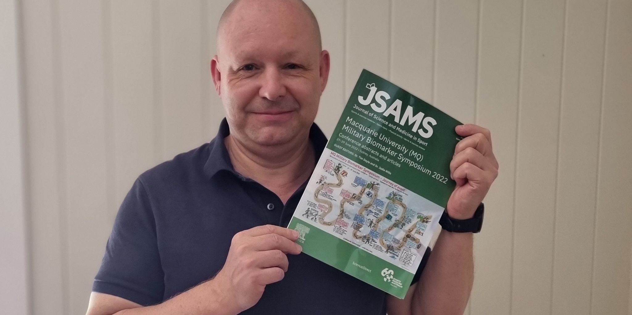 Professor Laurent Frossard holds a copy of the Journal of Science and Medicine in Sport in which his paper is published.