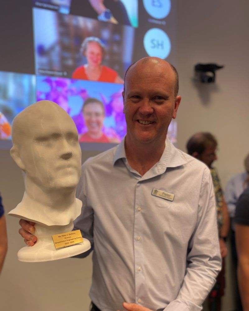 Peter Slattery holds a 3D-printed bust at his retirement celebration