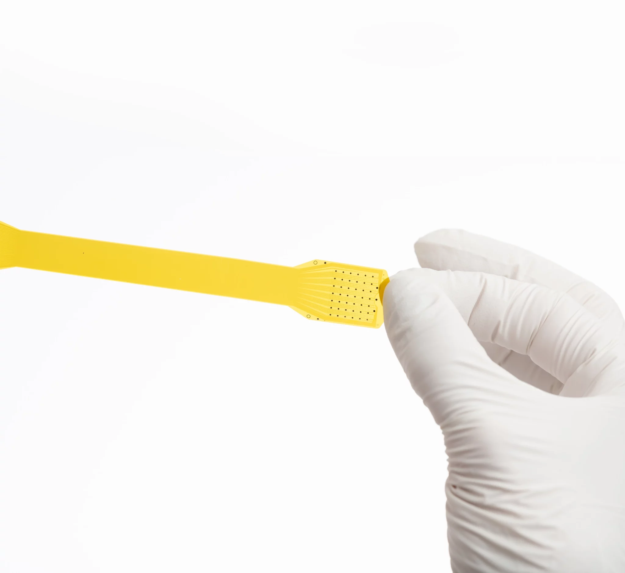 Hand in white surgical glove holds yellow Precision Neuroscience brain-computer interface device