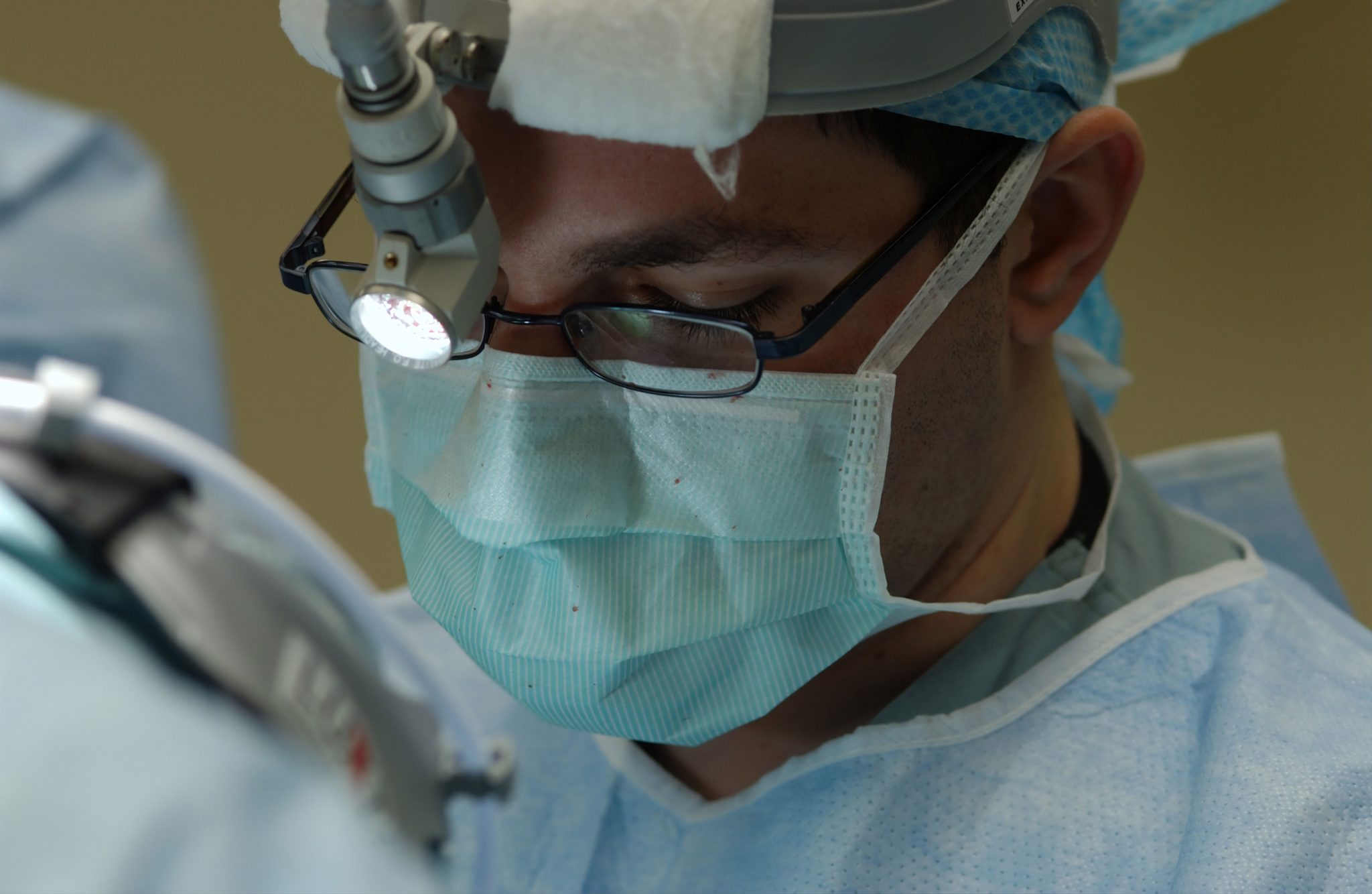 Close up photo of surgeon in surgical scrubs operating in a theatre.